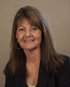 A woman smiling wearing a black blazer