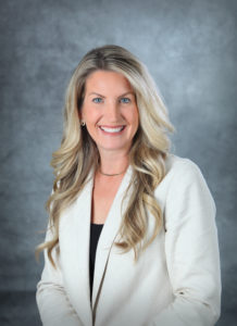 A woman smiling while wearing a formal blazer