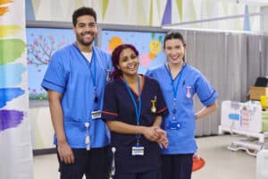 three pediatric nurses smiling in a children's ward of a hospital