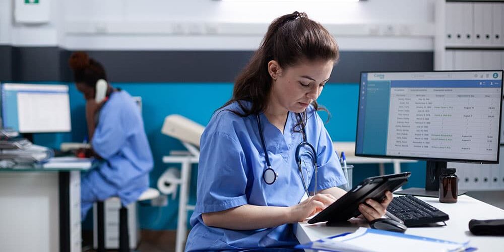 doctor reviewing information on tablet at work station